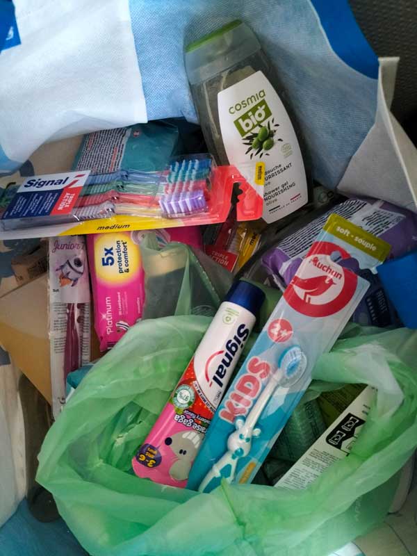 Produits d'hygiène dans un panier de collecte (brosses à dent, dentifrices, shampooing, ...)