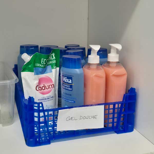 Une caisse de gels douche dans un placard en attendant leur distribution aux bénéficiaires